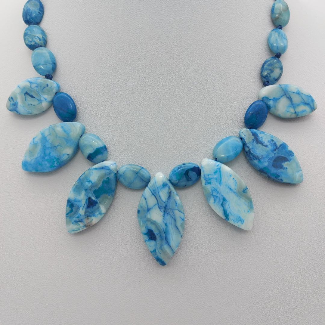 Close-up of seven marquise Blue Crazy Lace Agate drops with polished oval gemstones