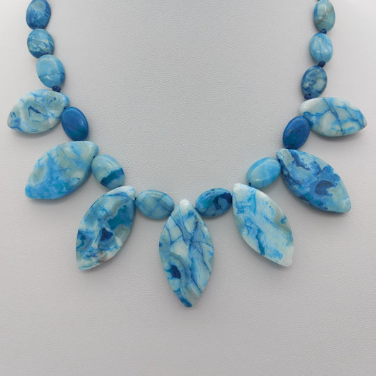 Close-up of seven marquise Blue Crazy Lace Agate drops with polished oval gemstones