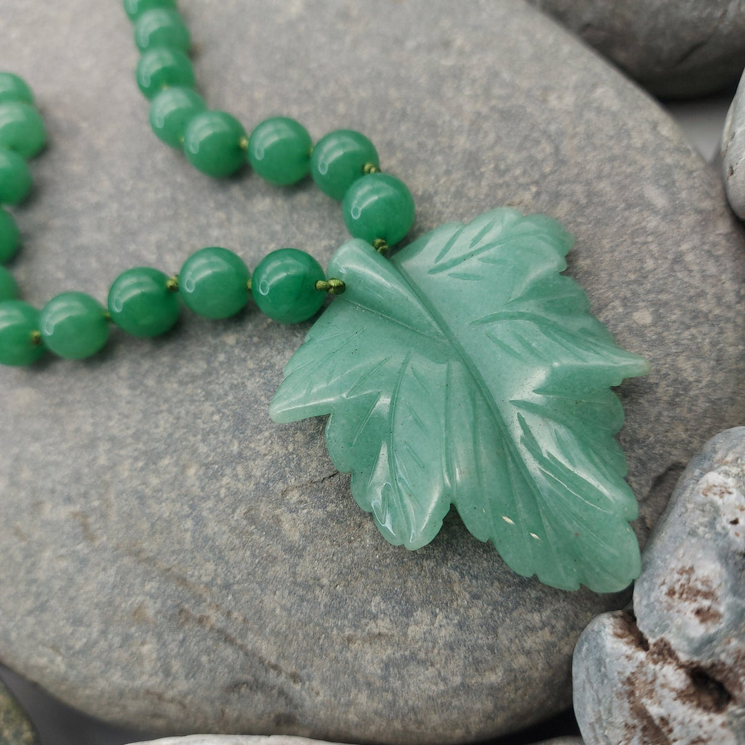 Close-up of genuine green aventurine carved leaf pendant with hand-knotted gemstone beads