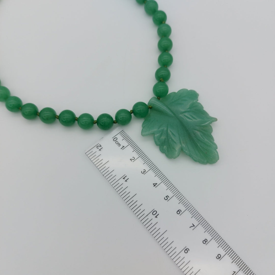 Large carved green aventurine leaf pendant photographed with ruler to show its approximate size