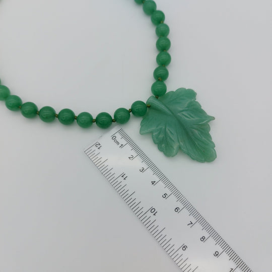 Large carved green aventurine leaf pendant photographed with ruler to show its approximate size