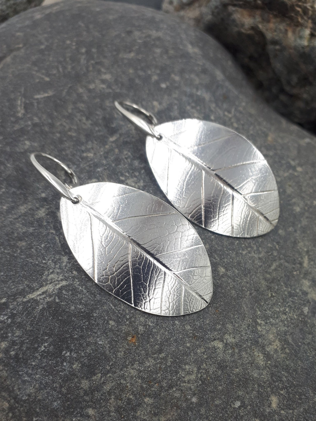Sterling silver leaf textured earrings close-up showing intricate botanical texture and artisan detail