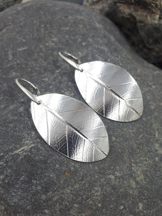 Sterling silver leaf textured earrings close-up showing intricate botanical texture and artisan detail