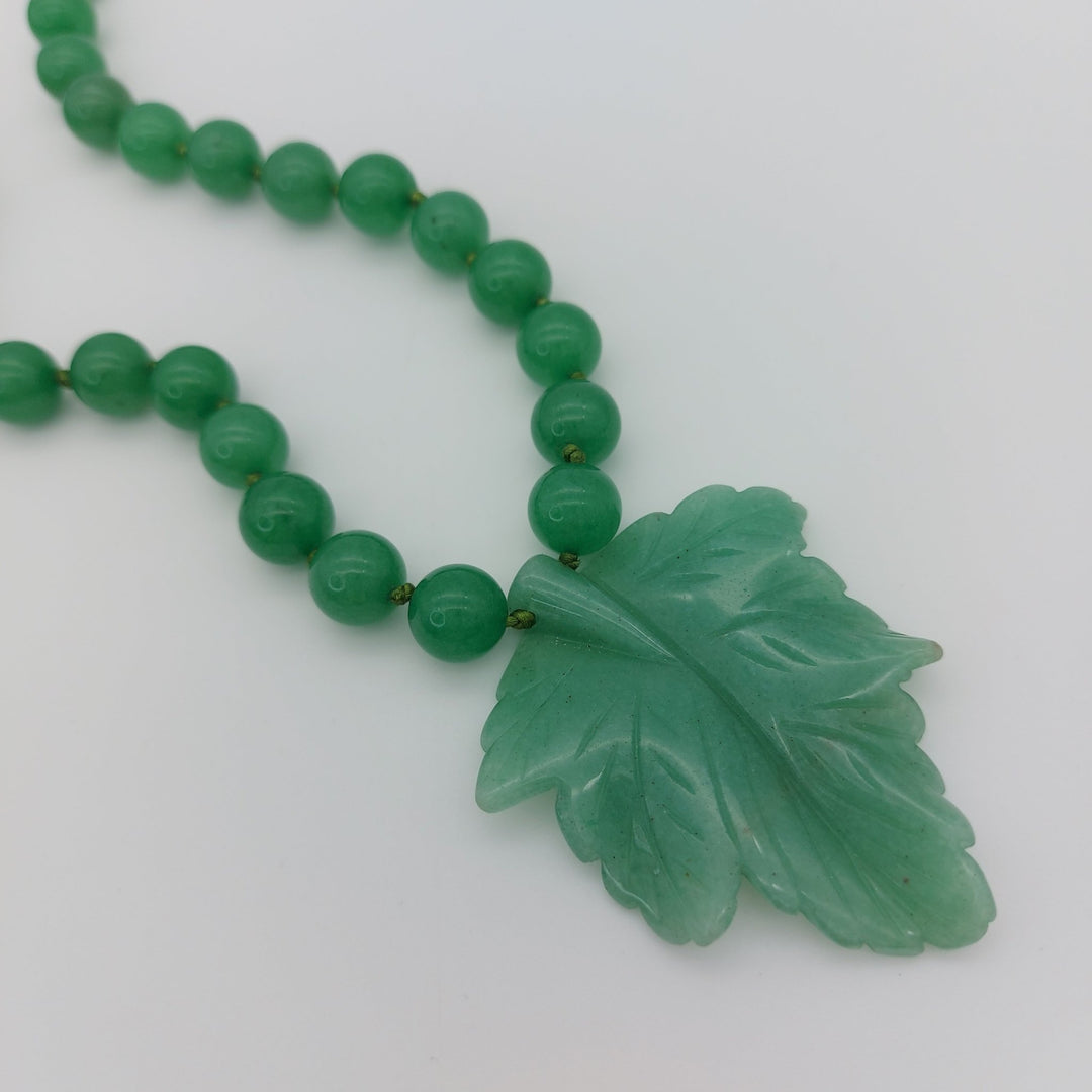 Close-up of natural green aventurine carved leaf pendant and round gemstone beads