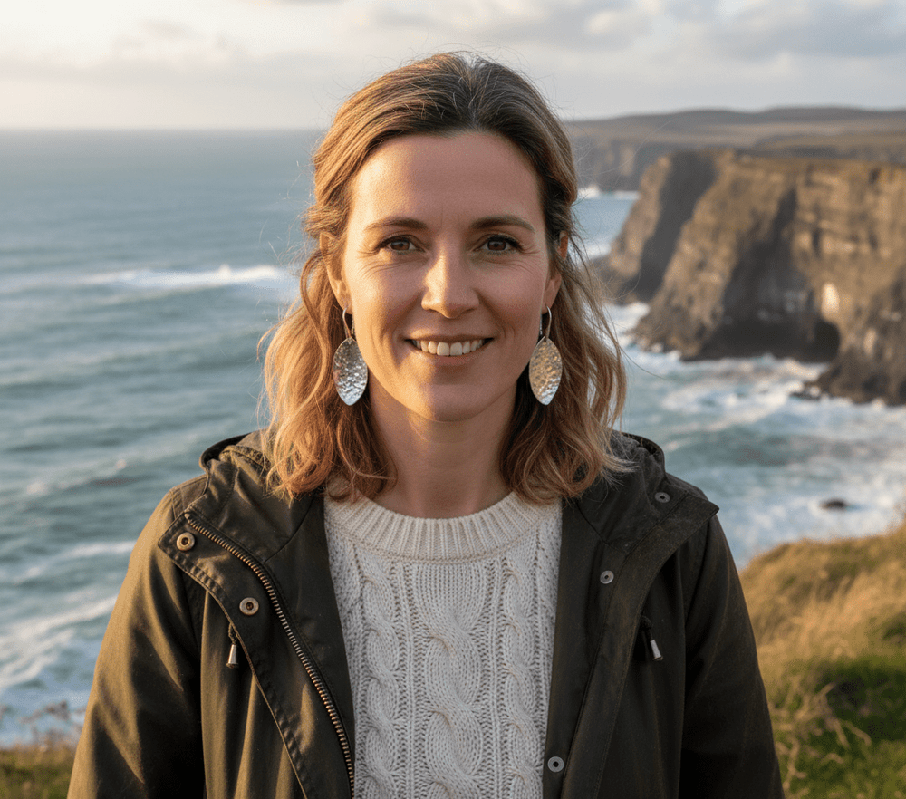Woman in coastal walk clothing wearing realistically-sized 5cm sterling silver leaf earrings on Welsh coast